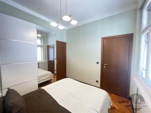 Prostorná ložnice s parketovou podlahou, vestavěné skříně a velkými okny, moderní design a světlé odstíny vytváří příjemný interiér.