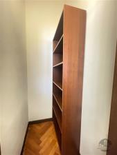 Úzká chodba s dřevěnou knihovnou, parketová podlaha, bílá omítka, ideální pro využití jako úložný prostor.