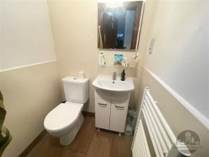 Kompaktní koupelna s moderním umyvadlem, dlažbou a světlými stěnami, vybavená topným tělesem a úložnou skříňkou pod umyvadlem.