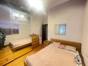 Ložnice s parketovou podlahou, vestavěnými skříněmi a moderním nábytkem, světlé zdi a útulný prostor, ideální pro relaxaci.