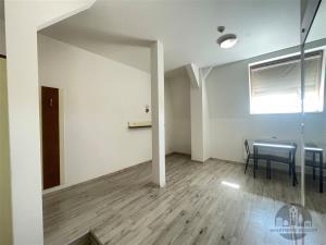 Světlá jídelna s moderní laminátovou podlahou, stůl pro dva, velké střešní okno, minimalistický design, dobré přírodní osvětlení.