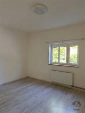 Světlá ložnice s moderní laminátovou podlahou, velkými okny a neutrálními barvami, ideální pro útulné bydlení.